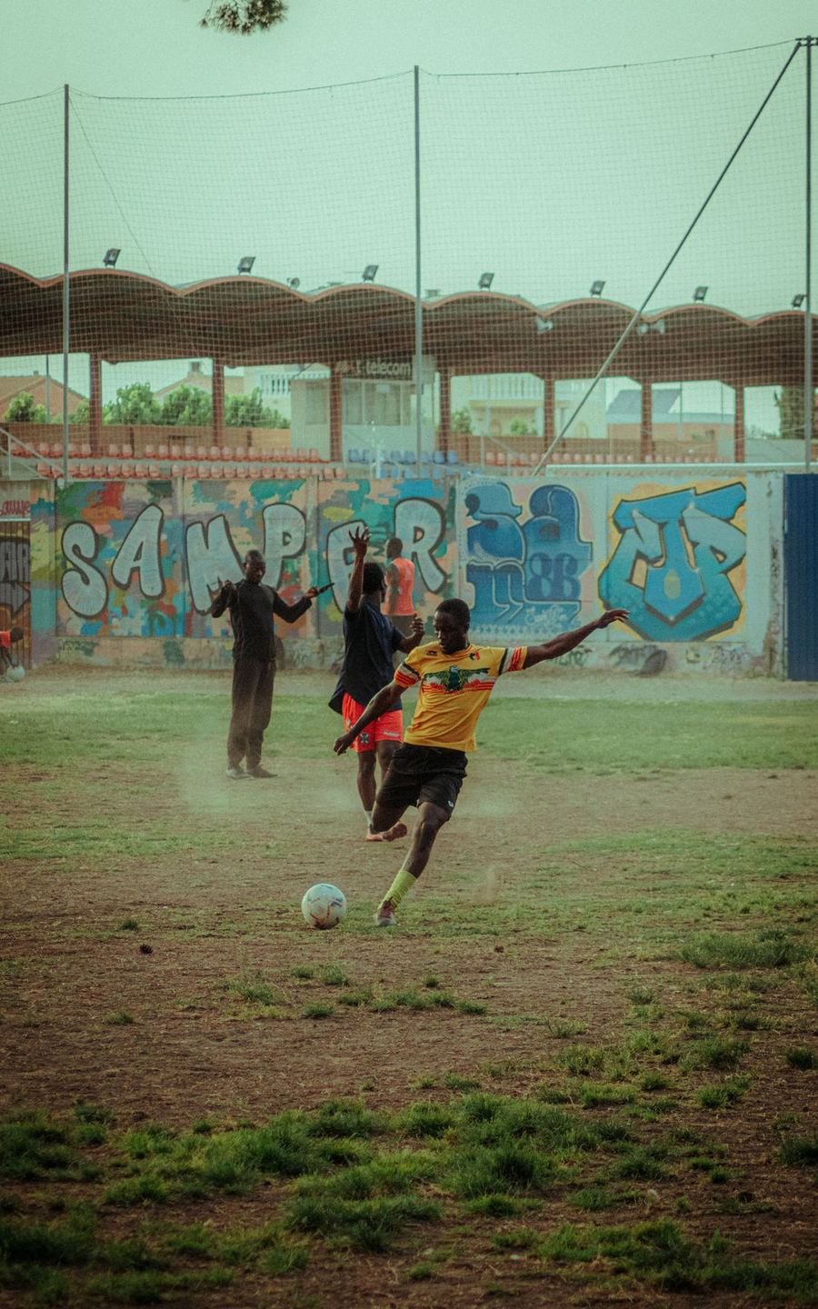 Match referees talking on a dusty pitch before kickoff